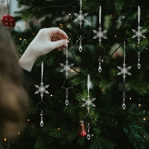 Close-up of clear acrylic snowflake and icicle ornaments hanging on a glowing Christmas tree