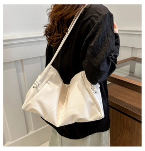 Detail of white soft leather hobo bag featuring embossed logo and side knot strap