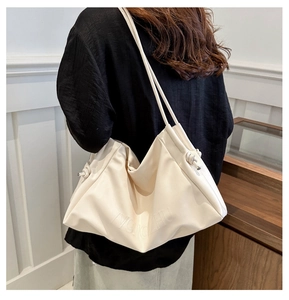 Rear view of a model wearing a cream pleated cloud tote bag with side knot details