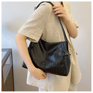 Detalle del relieve ZHONGGU en bolso tote de cuero negro con correas finas para hombro