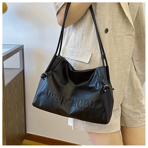 Detalle de las letras VVZHONGGU en relieve y cordón en el bolso tote minimalista negro