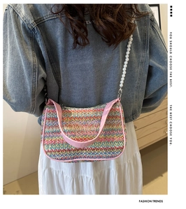 Detail of rainbow woven straw bag featuring pink butterfly embroidery and pearl strap