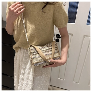 Détail d'un sac bandoulière tissé avec sangle en perles et broderie papillon rose