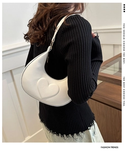 Gros plan d'un sac sous le bras blanc avec cœur en relief 3D et bandoulière élégante