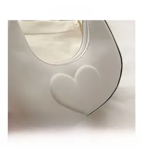 Gros plan détaillé du gaufrage cœur 3D sur un sac demi-lune blanc en similicuir