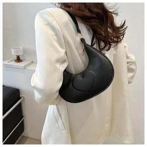 Gros plan du sac croissant noir avec motif de cœur embossé et anneaux métalliques dorés