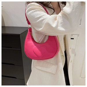 Détail du sac hobo rose avec motif cœur embossé et finitions dorées porté à l'épaule