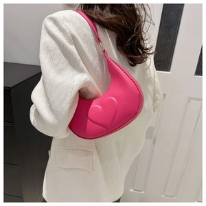 Détail du relief en cœur sur un sac à épaule en cuir fuchsia en forme de croissant