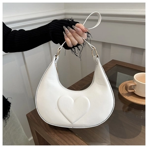 Détail du sac croissant en cuir blanc avec cœur embossé et anneaux dorés élégants