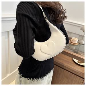 Détail du sac à bandoulière blanc en demi-lune avec relief cœur porté par un mannequin