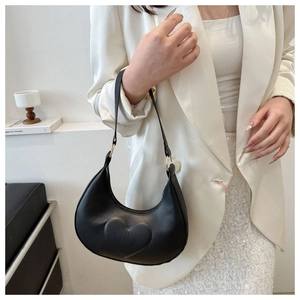Détail d'un sac hobo noir en forme de croissant avec gaufrage cœur 3D et anneaux dorés
