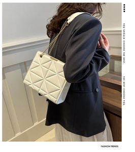 Detail view of white quilted tote bag with geometric pattern and golden chain strap