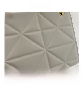 Close-up of white quilted tote bag with geometric star pattern and gold metal eyelets