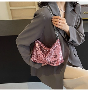 Close-up of pink sequin crescent bag with silver chain strap shown on a model