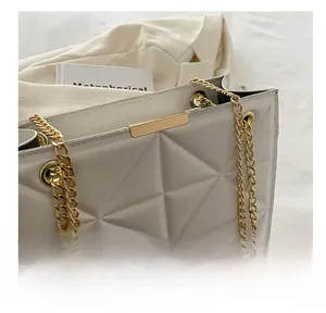 Detailed close-up of white quilted tote bag featuring gold chain strap and geometric pattern