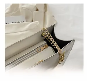 Detail of smooth gold zipper and chain strap on ivory large capacity tote bag