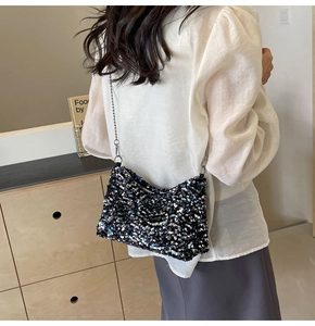 Detail of sequin shoulder bag with silver chain strap worn by a model in a room