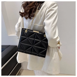 Detail of black geometric quilted handbag with gold chain strap and matte leather finish