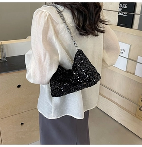 Detail of black sequin shoulder bag with silver chunky chain strap on a model