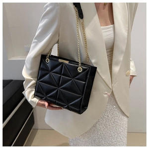 Detail of black geometric quilted bag with elegant gold chain strap and metal trim