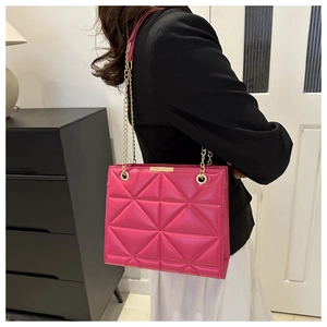 Close-up of fuchsia quilted geometric bag with glossy finish and gold chain strap