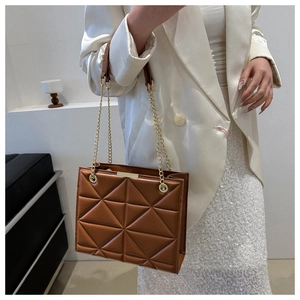 Macro detail of brown quilted tote bag showing geometric stitching and gold chain strap