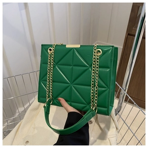 Detail of green quilted tote bag with geometric stitching and golden metal chain strap
