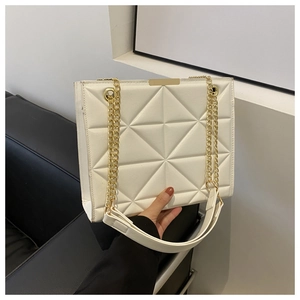 Close-up of a white quilted tote bag with golden metal trim and elegant chain strap