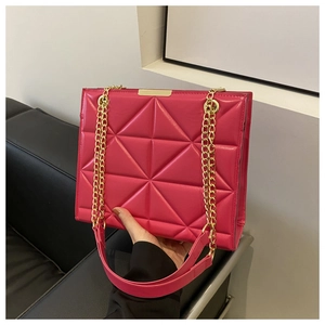 Detail of fuchsia quilted tote bag featuring golden metal chain and geometric pattern