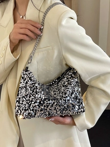 Sparkly sequin shoulder bag with chunky silver chain strap worn by a model in a suit