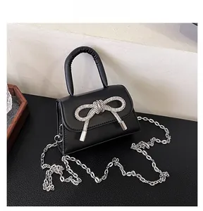 Detail of black faux leather mini bag featuring a large sparkling rhinestone bow buckle