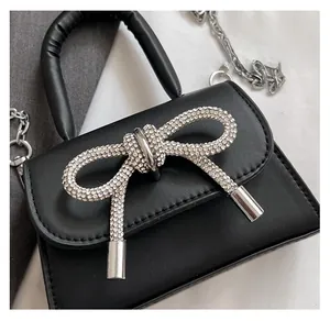 Close-up of elegant black leather mini bag featuring a large sparkling rhinestone bow