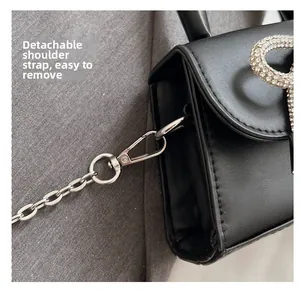 Close-up of silver metal hook and removable chain strap on black leather handbag