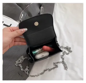 Detail showing internal capacity of the black mini crossbody bag with lipsticks and earbuds