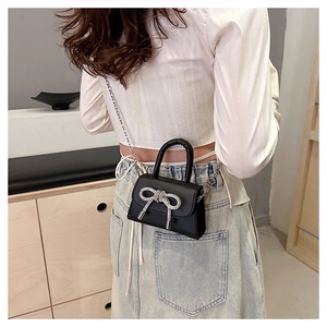 Dettaglio di una mini borsa a tracolla nera con fiocco di cristallo su un modello reale