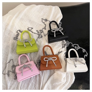Detailed view of mini crossbody bags with rhinestone bows and metal chain straps