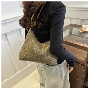 Close-up of olive green woven shoulder bag with knotted strap detail and matte texture