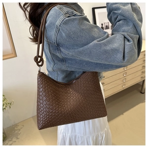 Close-up of dark brown woven leather texture and knot detail on a shoulder tote bag