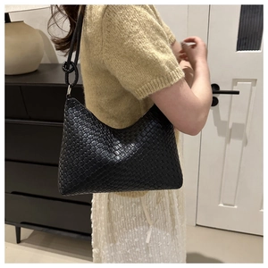 Detail of black woven leather shoulder bag with knotted strap and silver hardware accents