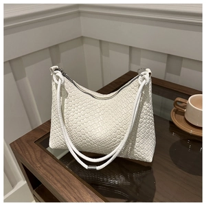 Détail du sac hobo tissé blanc avec fermeture éclair argentée sur bois foncé