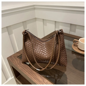 Détail d'un sac cabas tressé marron foncé avec fermeture éclair et anneaux métalliques