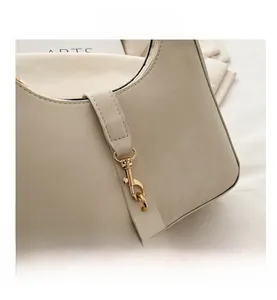 Close-up of golden metal buckle and premium beige leather texture on underarm bag