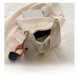 Internal view of cream shoulder bag showing zipper pocket and metal anti-theft hook