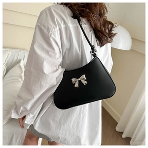 Close-up of black PU underarm bag featuring a silver metal bow and knotted strap detail