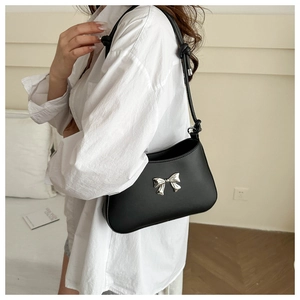 Detail of black bow shoulder bag with silver hardware and knotted strap on model