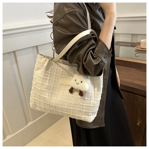 Detail of white woven texture tote bag with leather strap and plush cloud pendant