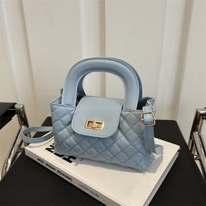Close-up of light blue quilted crossbody bag featuring a golden metallic twist lock