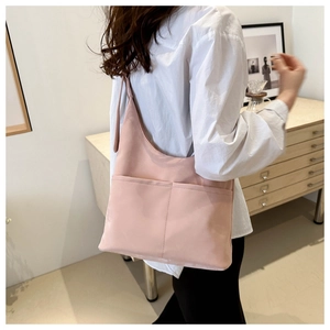 Pink large capacity tote bag shown from side view on model in minimalist home setting
