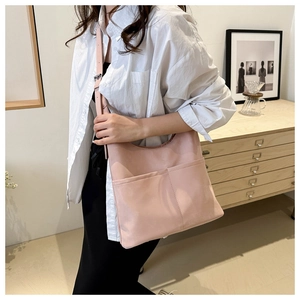 Close-up of a light pink leather bucket tote bag with adjustable strap in home setting