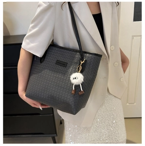 Detailed view of woven leather tote bag with fashion label and white pompom charm
